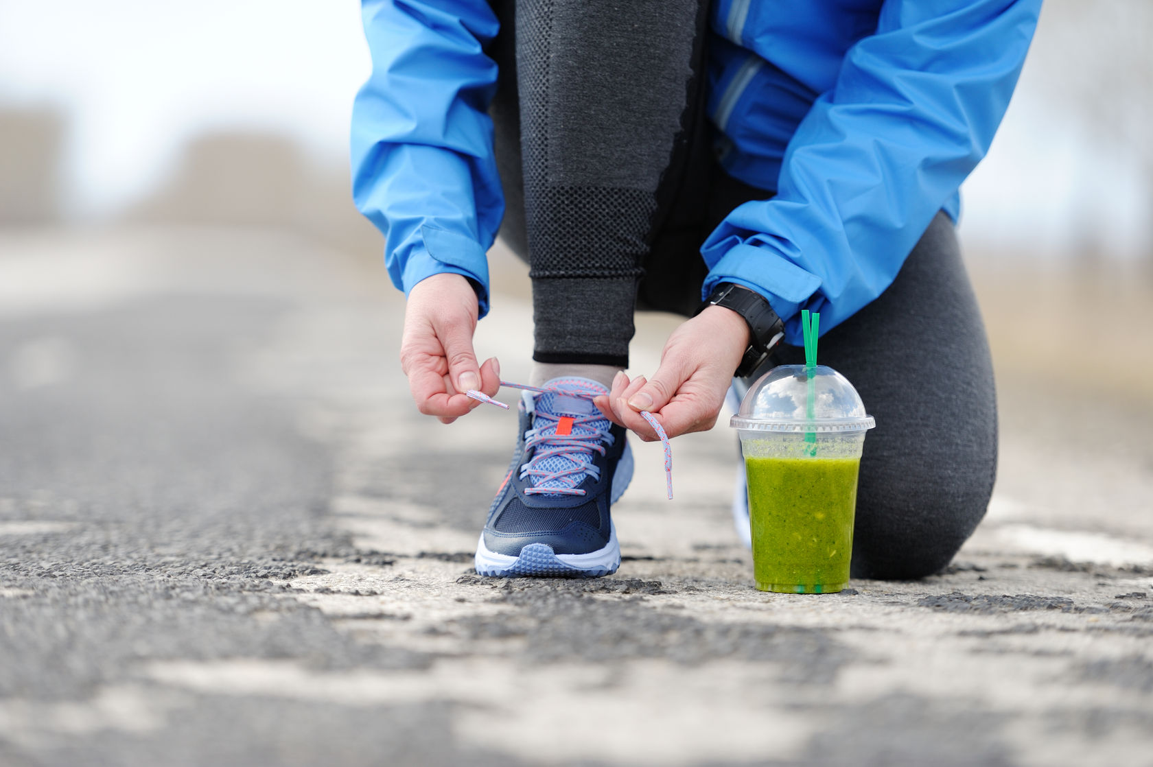 70543803 - green detox smoothie cup and woman lacing running shoes before workout. fitness and healthy lifestyle concept.